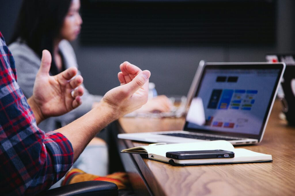 A person gesturing in front of a laptop