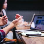 A person gesturing in front of a laptop