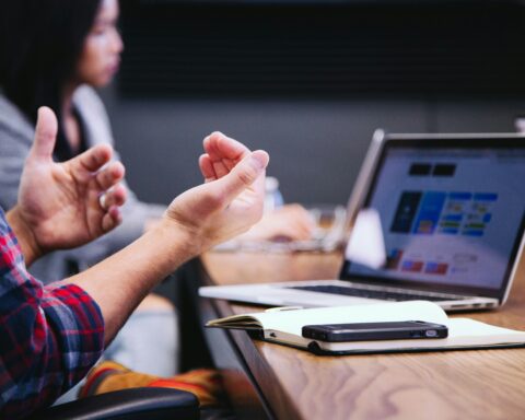 A person gesturing in front of a laptop