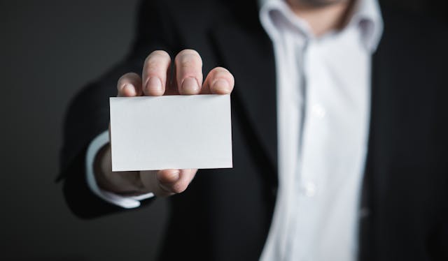 A man holding up an empty business card.